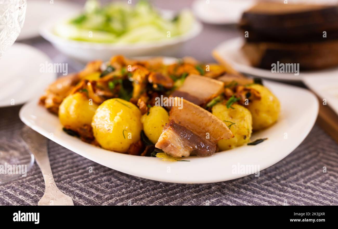 baked potatoes with chanterelles and bacon served with herbs on white