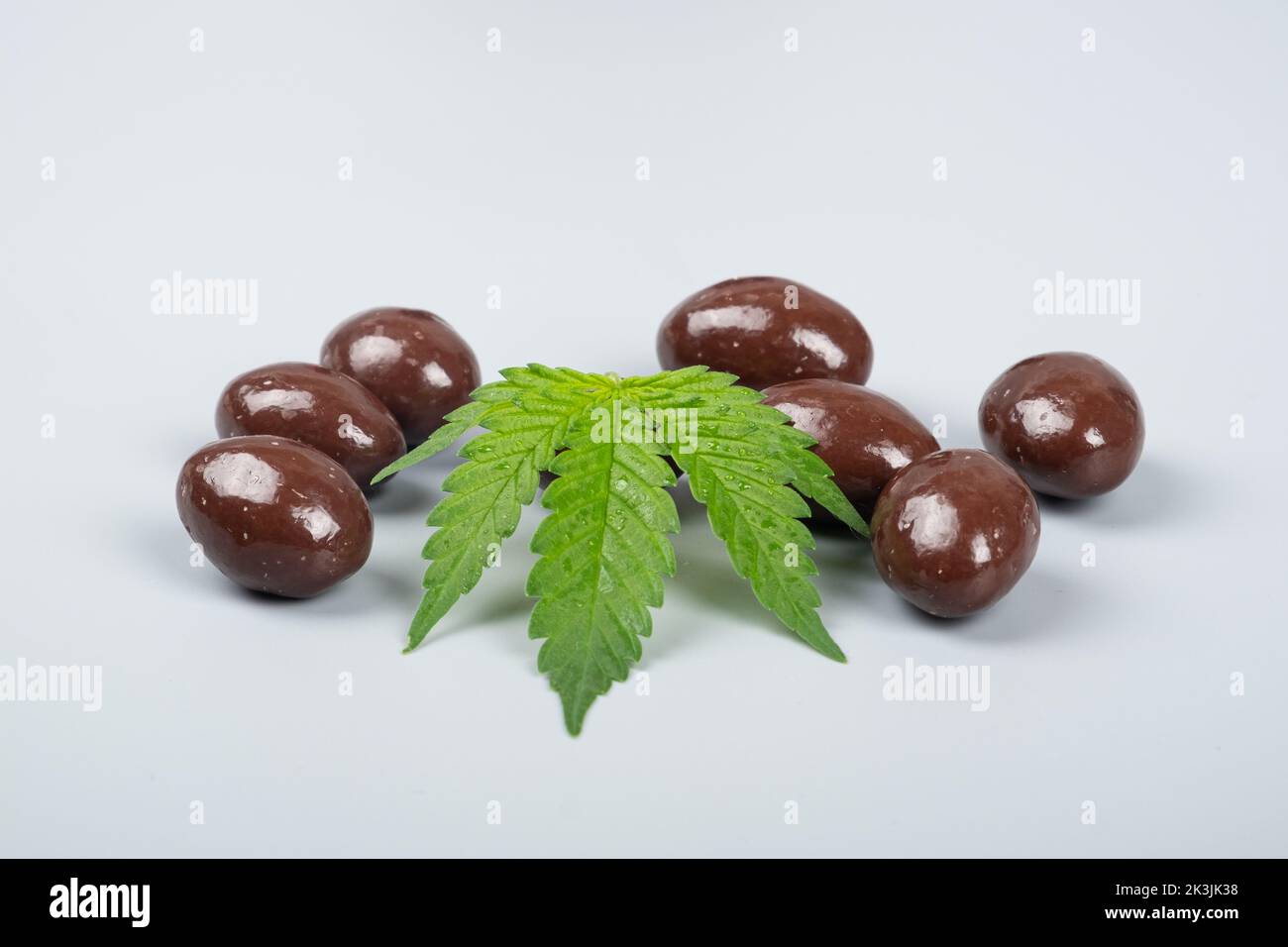 chocolate candies with thc and cbd, recreational drugs and green marijuana leaf. Stock Photo