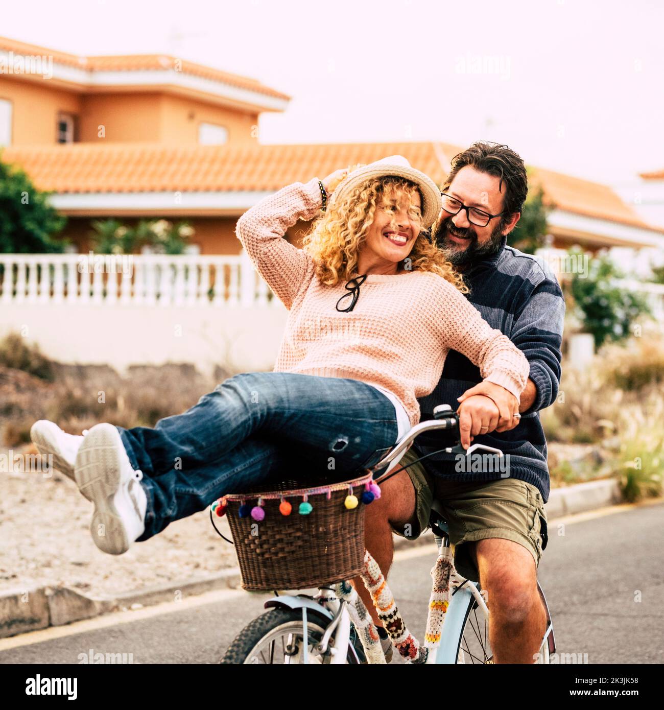 Two happy and active person man and woman enjoying bike ride together having fun and laughing a lot. Young mature couple use green eco transport. Male Stock Photo