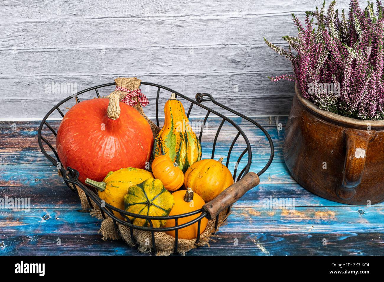various ornamental gourds in an old wire basket decorated with a winter heather Stock Photo