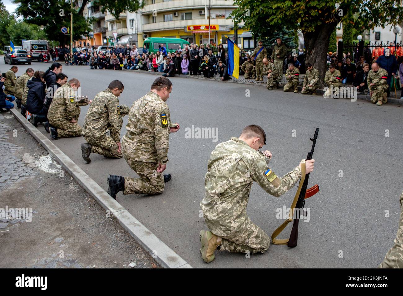 PERECHYN, UKRAINE - SEPTEMBER 25, 2022 - Servicemen kneel to pay their last respects to Senior Lieutenant Armen Petrosian, 50, who died while liberati Stock Photo