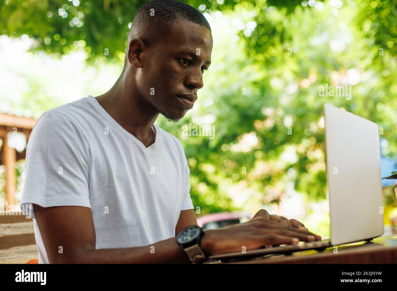 Confident, serious, calm multicultural man working online using laptop outdoors. E-learning, online internet education Stock Photo