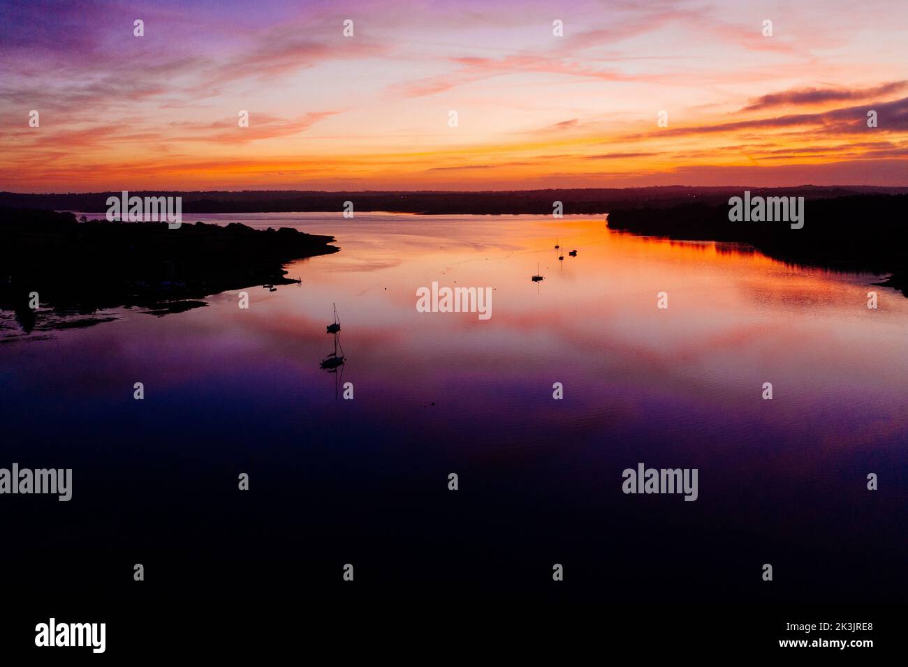 A dramatic sunset with a colorful cloudy sky and its reflection on a ...