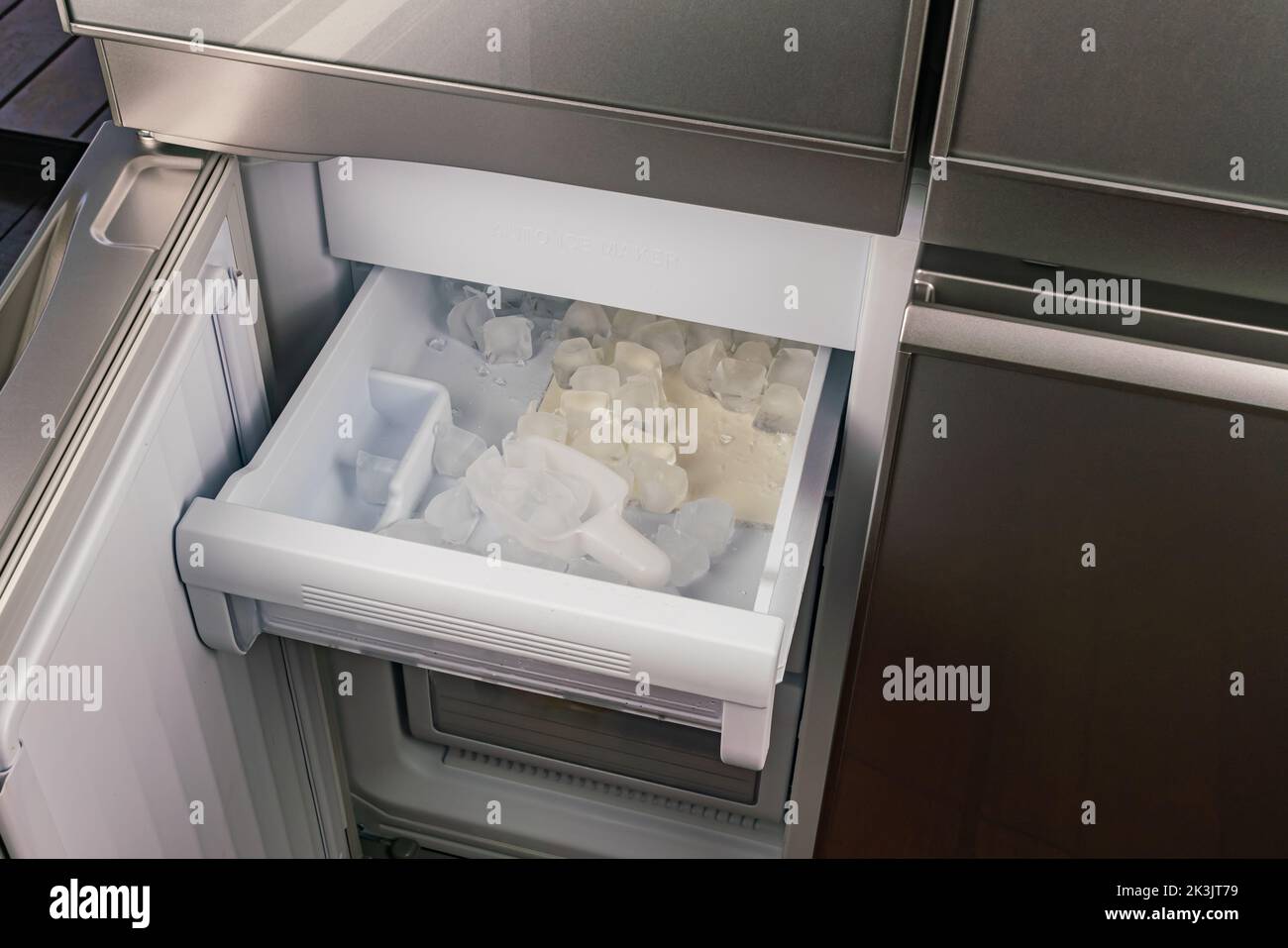 Ice cubes in the tray inside of automatic ice maker in a modern refrigerator. Stock Photo
