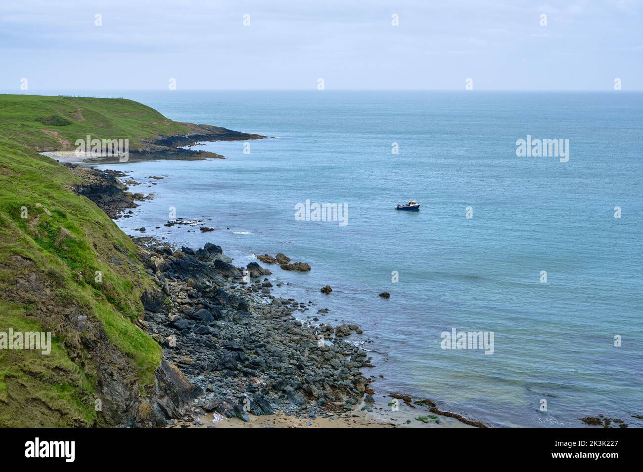 A fishing boat in a bay along the coast of the Llyn Peninsular from the Wales Coast Path Stock Photo