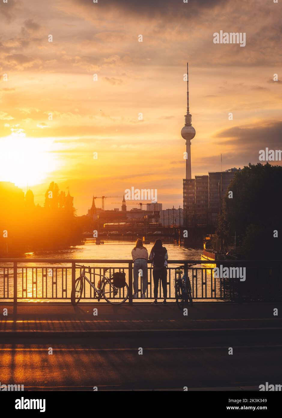 A vertical shot of two bikers on a bridge at golden hour in Berlin Stock Photo