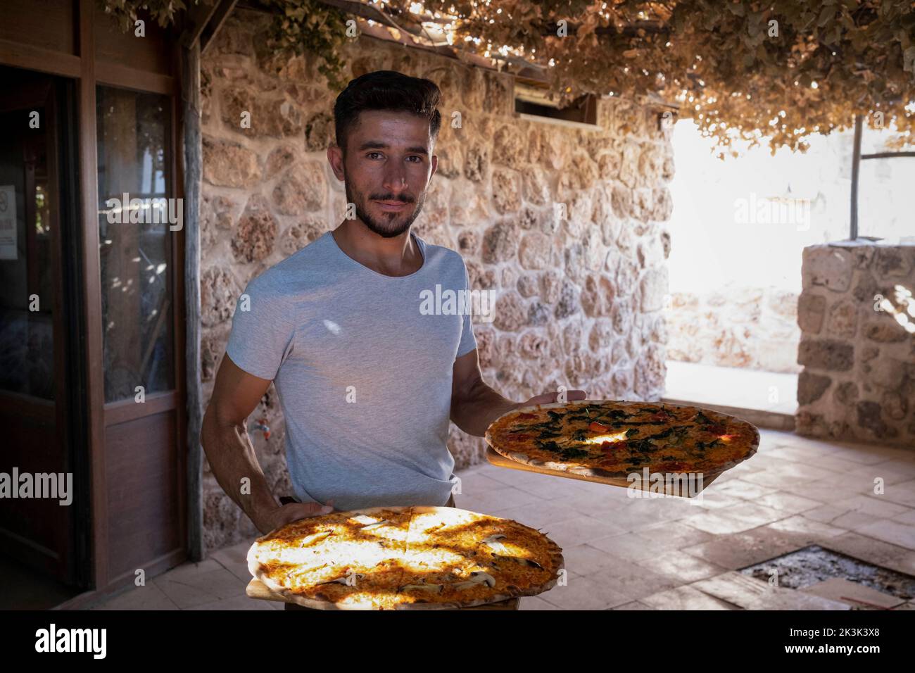 Yunus (27), a worker at Kafro's Pizza seen holding pizzas. There is a
