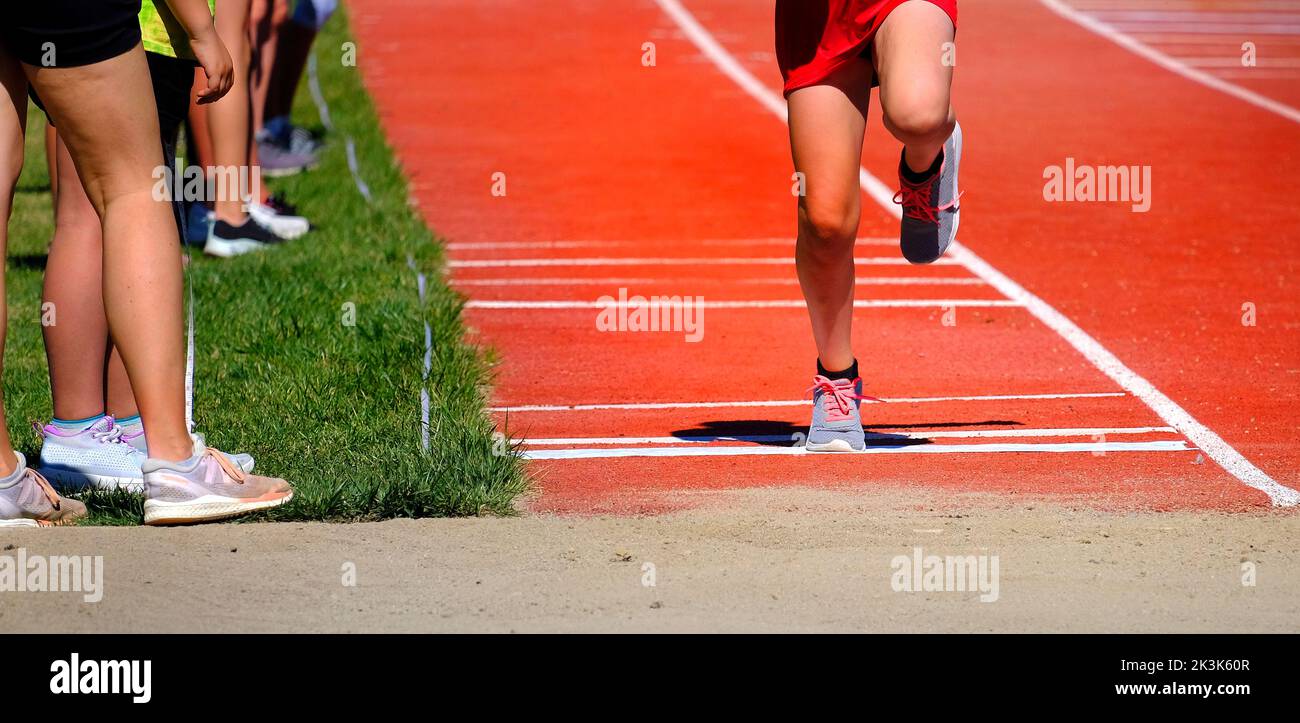 Long jump competition in track and field athlete wearing red shorts running and jumping Stock Photo