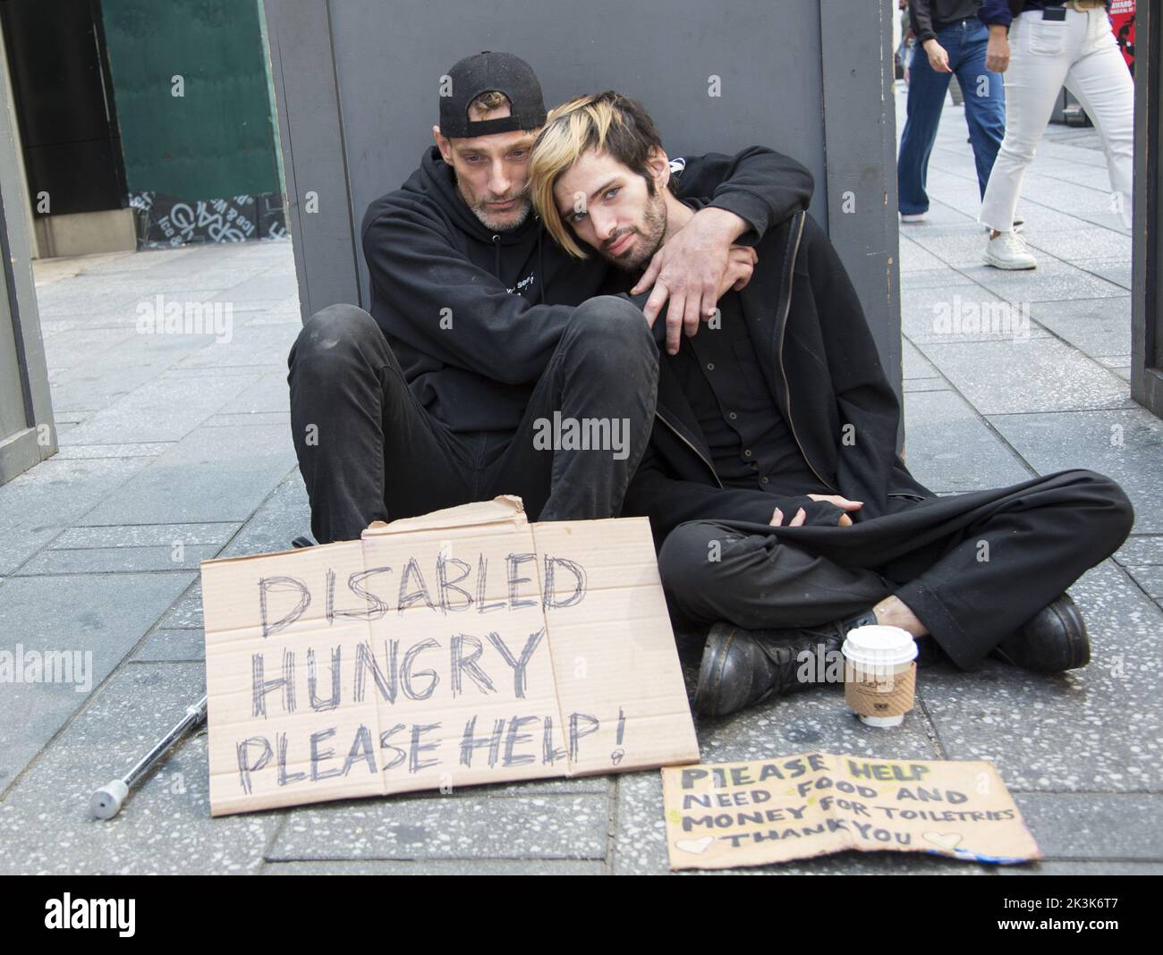 Homeless disabled man with partner ask for help sitting on the sidewalk