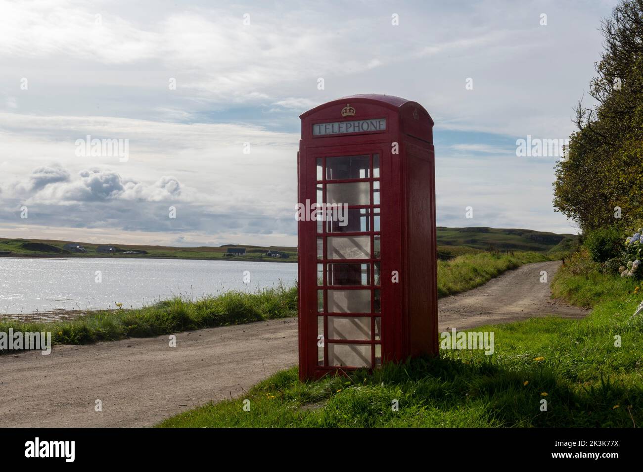September 2022: Isle of Canna, Inner Hebrides, Scotland The old red phone box on the road along the shore Stock Photo