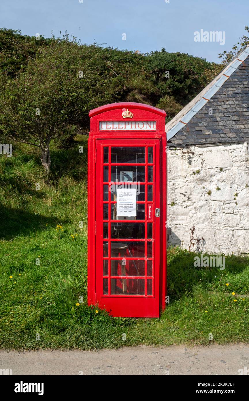 September 2022: Isle of Canna, Inner Hebrides, Scotland The old red phone box on the road along the shore Stock Photo