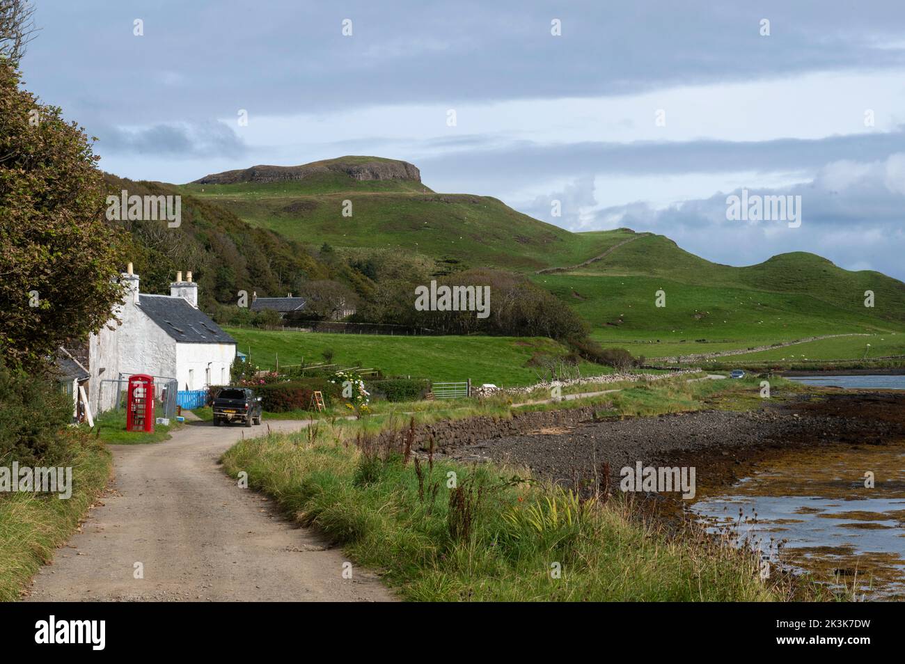 September 2022: Isle of Canna, Inner Hebrides, Scotland The old red phone box and post office on the road along the shore Stock Photo