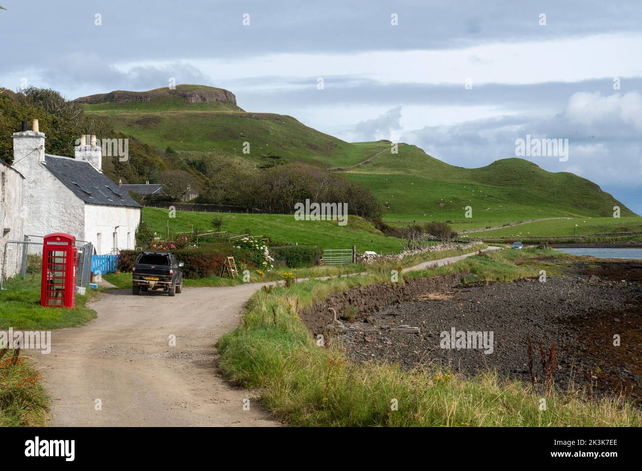 September 2022: Isle of Canna, Inner Hebrides, Scotland The old red phone box and post office on the road along the shore Stock Photo
