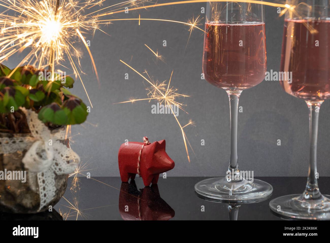 New Year's greetings with lucky clover, sparkling wine, sparkler and