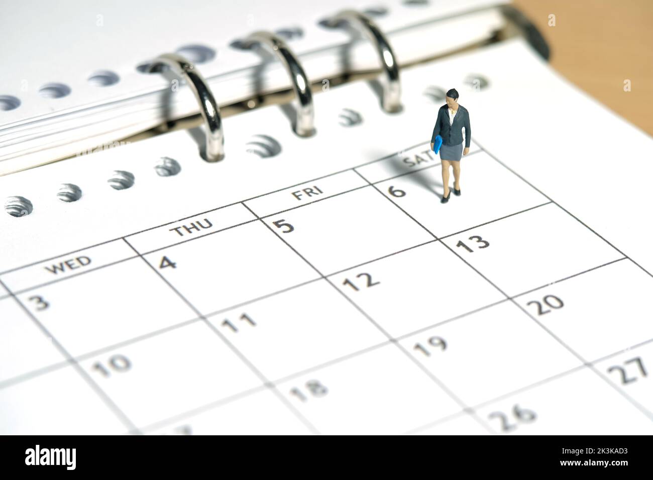 Miniature people toy figure photography. Work schedule concept. A businesswoman standing walking above calendar monthly planer. Isolated on white back Stock Photo
