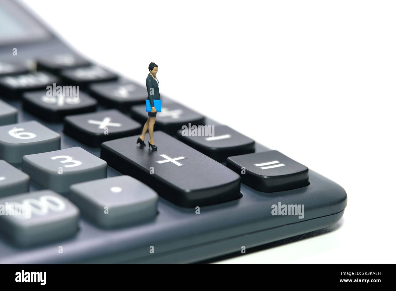 Miniature people toy figure photography. A businesswoman standing above calculator. Isolated on white background. Image photo Stock Photo