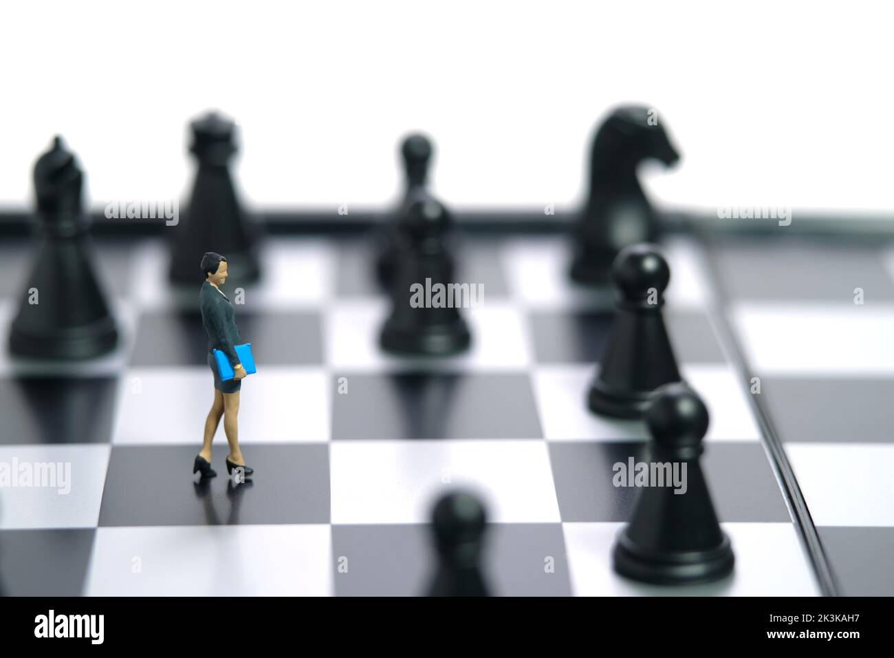 Miniature people toy figure photography. A businesswoman walking above chessboard in the middle of chess piece. Isolated on white background. Image ph Stock Photo