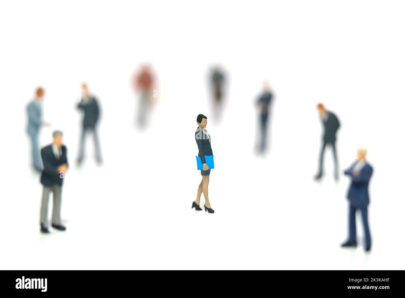 Miniature people toy figure photography. Women empowerment concept. A businesswoman standing in the middle of male people crowd. Isolated on white bac Stock Photo