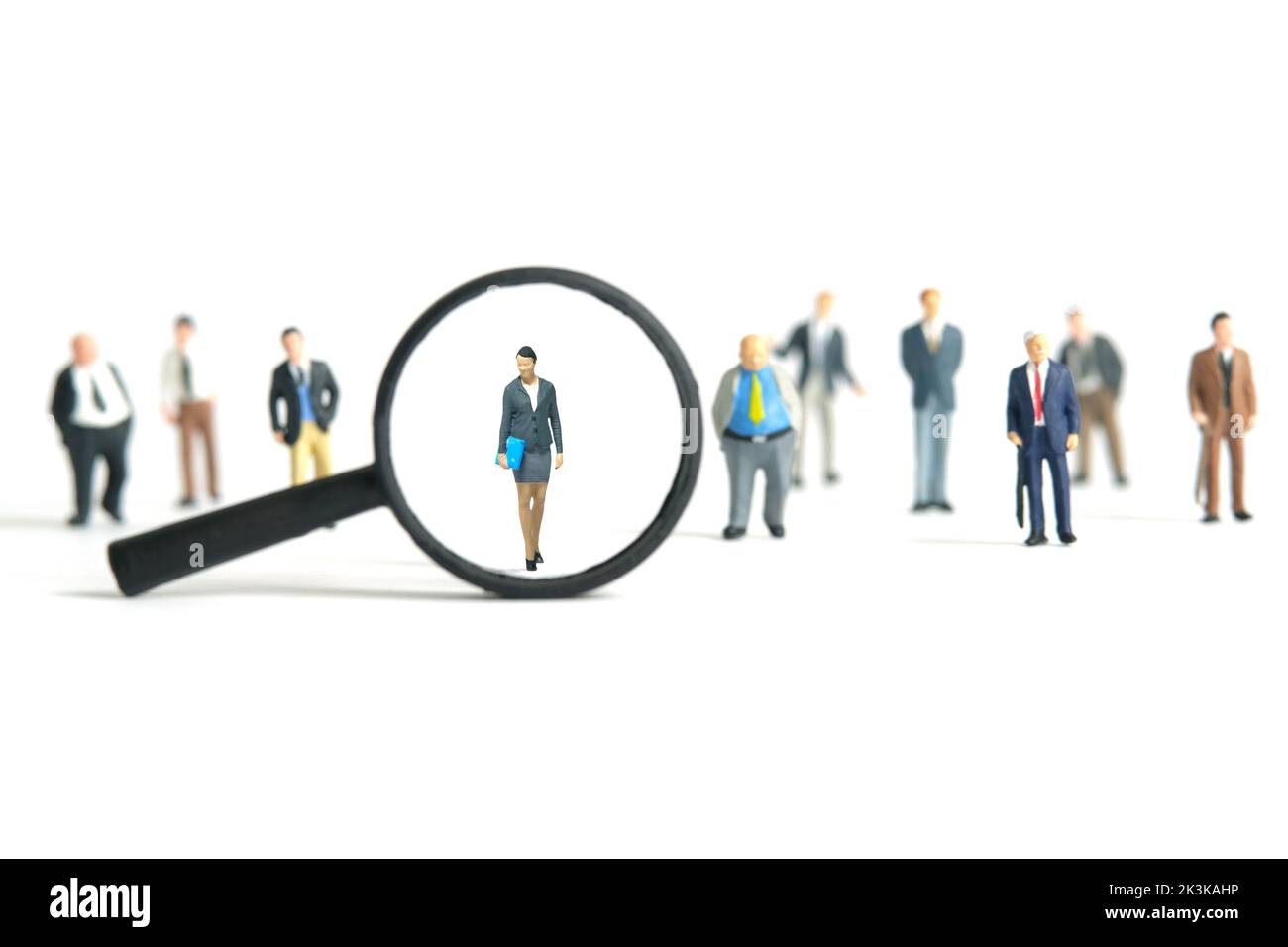 Miniature people toy figure photography. Women leader search. A businesswoman standing in the middle of male people crowd with magnifier glass. Isolat Stock Photo