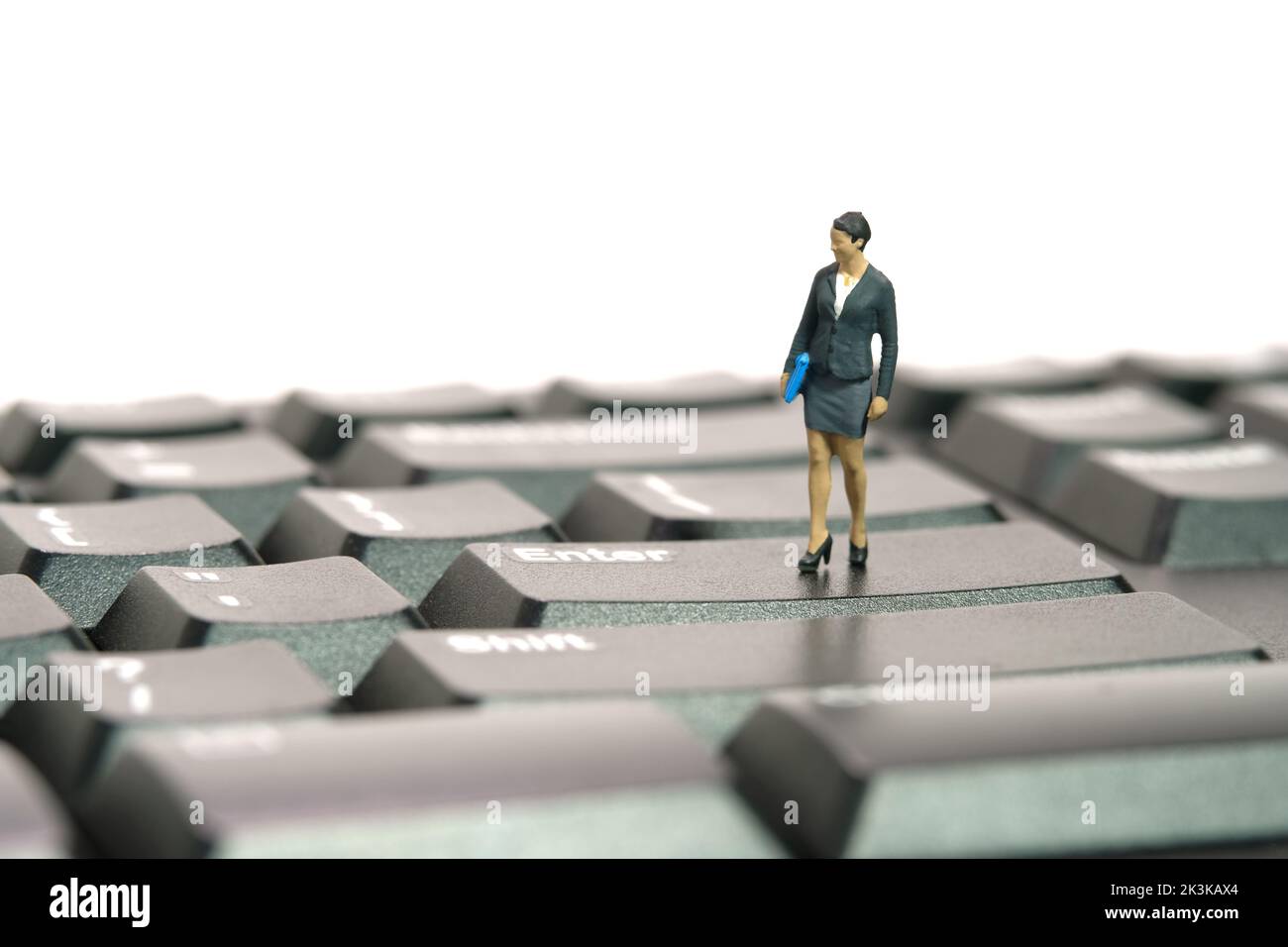 Miniature people toy figure photography. Typing job concept. A businesswoman standing above black keyboard. Isolated on white background. Image photo Stock Photo