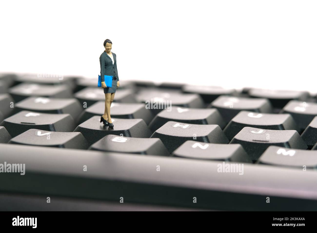 Miniature people toy figure photography. Typing job concept. A businesswoman standing above black keyboard. Isolated on white background. Image photo Stock Photo