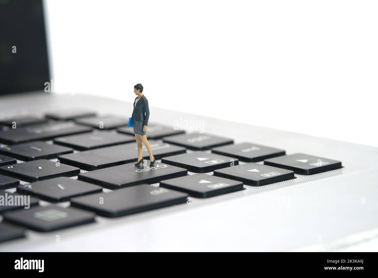 Miniature people toy figure photography. A businesswoman standing above notebook laptop keyboard. Isolated on white background. Image photo Stock Photo