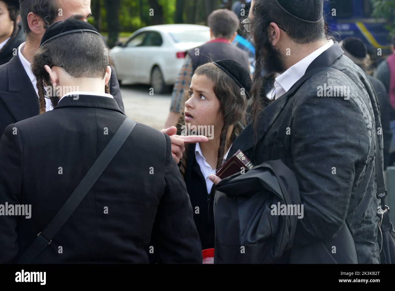 UMAN, UKRAINE - SEPTEMBER 25, 2022 - A boy stays by a group of men as Hasidic pilgrims gather for the celebration of Rosh Hashanah, or the Jewish New Stock Photo