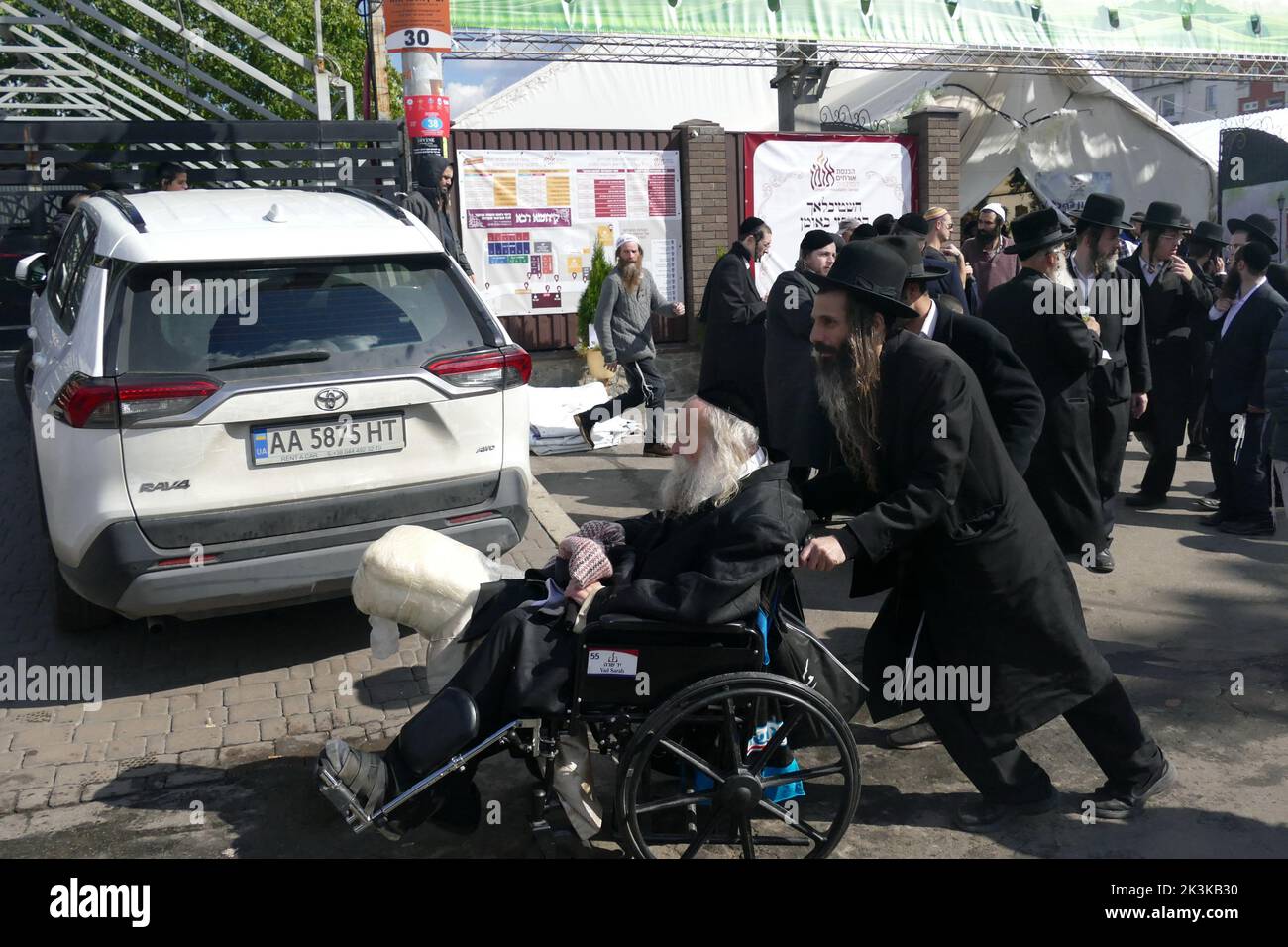 UMAN, UKRAINE - SEPTEMBER 25, 2022 - A Hasidic pilgrim pushes a wheelchair for an old man in the street before the celebration of Rosh Hashanah, or th Stock Photo