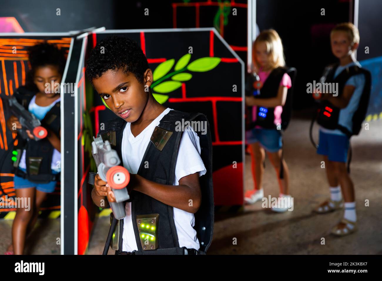 Portrait of happy cheerful preteen boy with laser pistol posing in laser tag labyrinth Stock Photo