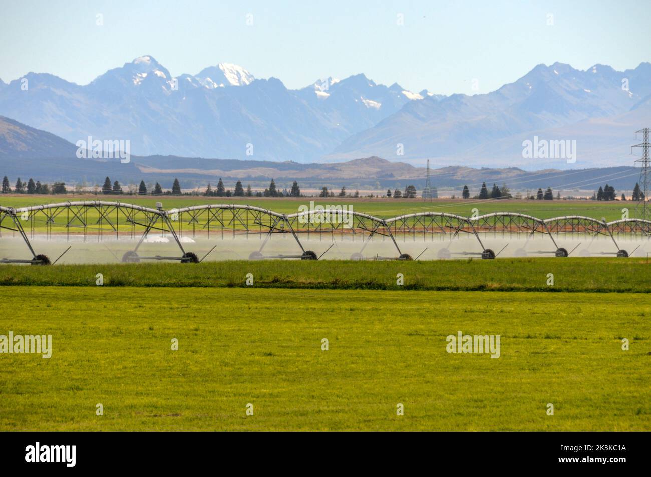 A long agricultural water feeding system being used on a cattle farm in Mackenzie country with a backdrop of the Southern Alps on the south island of Stock Photo