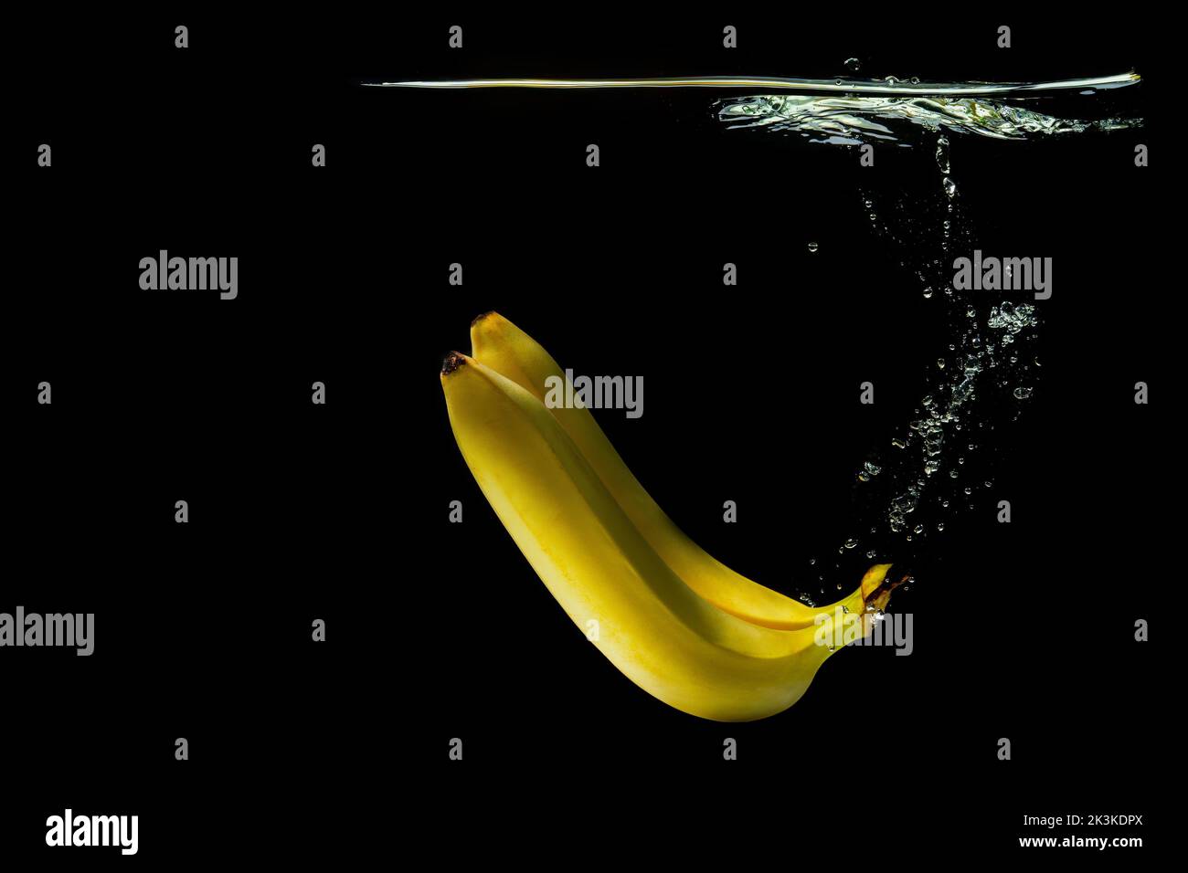 Two ripe bananas floating underwater isolated on black background Stock