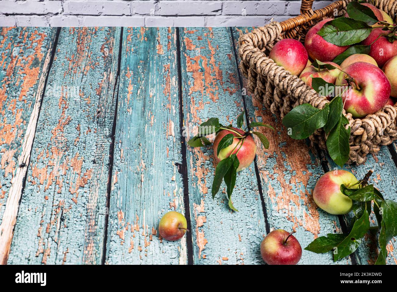 decorative plaited basket with fresh, red apples stands on an old tabletop Stock Photo