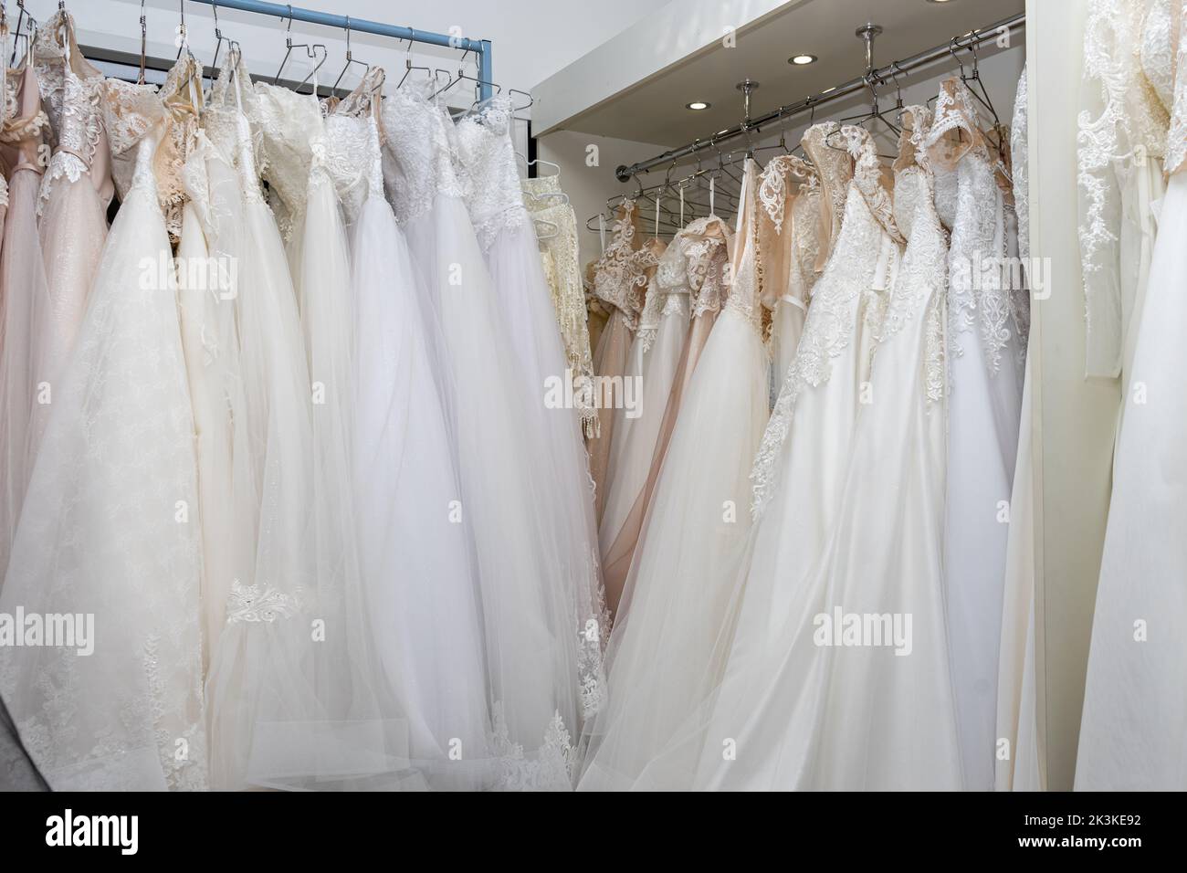 White and cream wedding dresses on a hanger in a bridal boutique. Close up Stock Photo