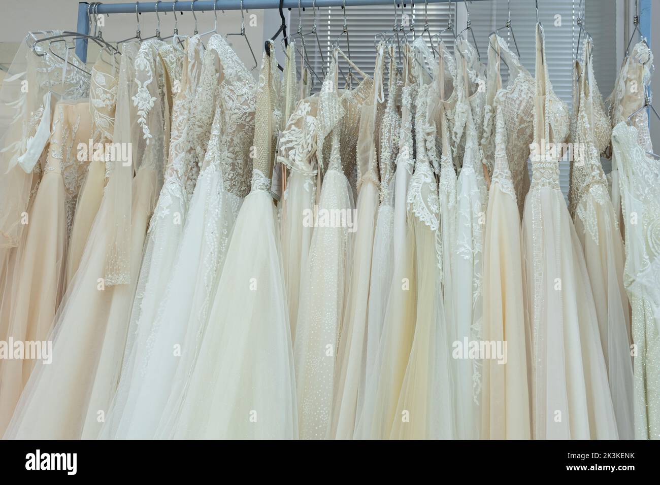 White and cream wedding dresses on a hanger in a bridal boutique. Close up Stock Photo