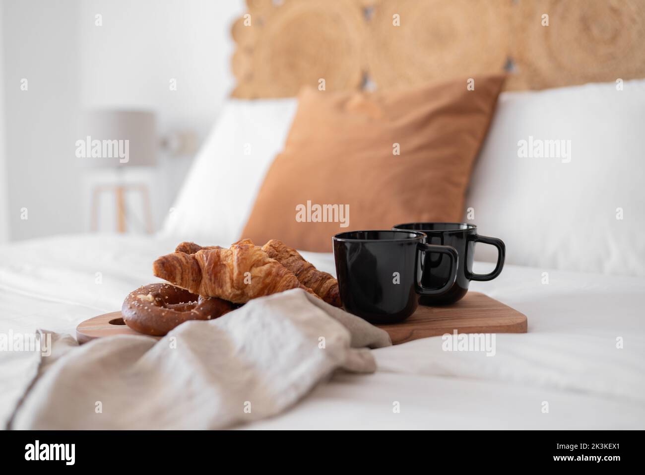 A croissant with coffee on bed in minimalistic setting Stock Photo