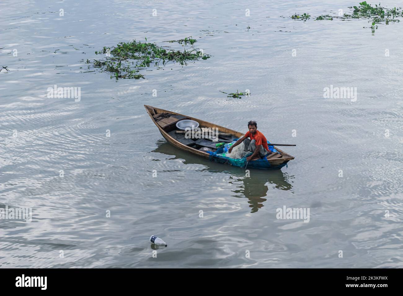 Bangladeshi traditional fishing boat on sunset. Fisherman in small boat on sea. Stock Photo