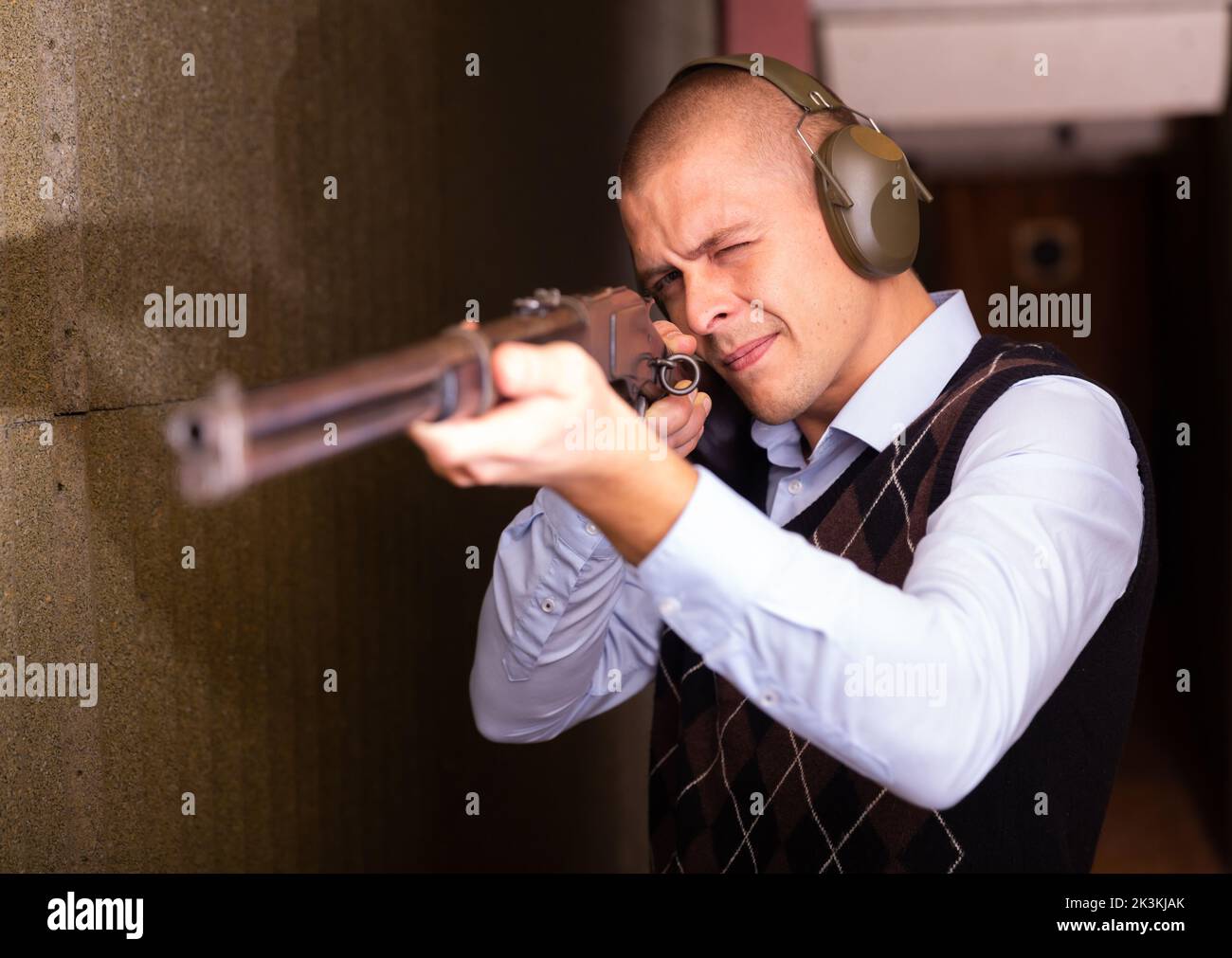 Confident shooter sighting in or zeroing shotgun in shooting gallery Stock Photo