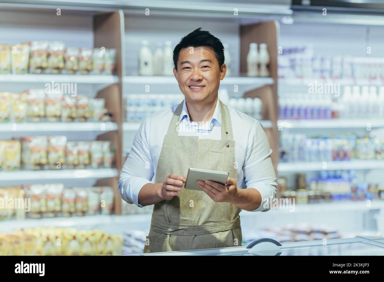 Portrait of a young handsome Asian man, shop owner, a supermarket