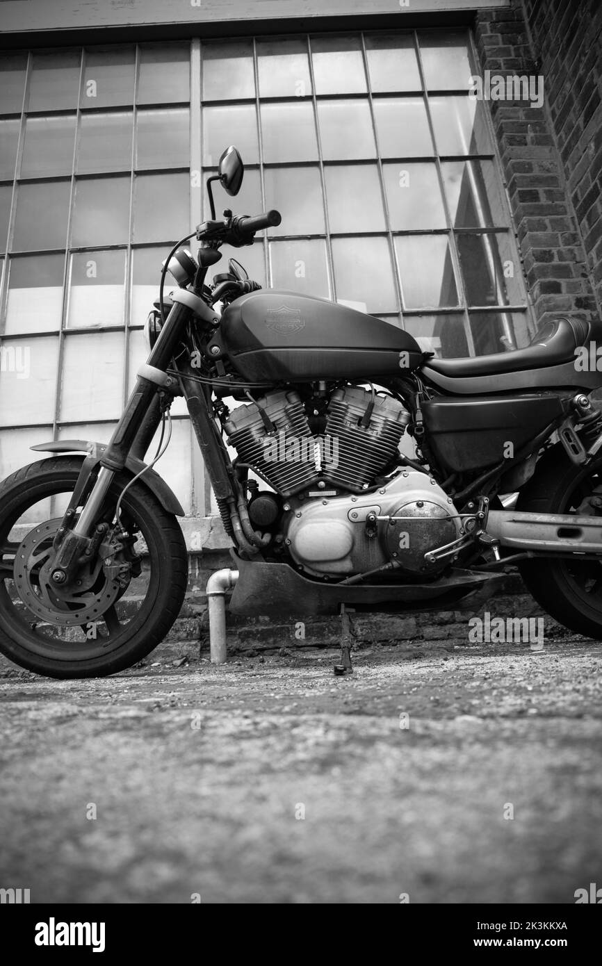 A vertical of a motorbike against a brick wall and window in black and white. Stock Photo