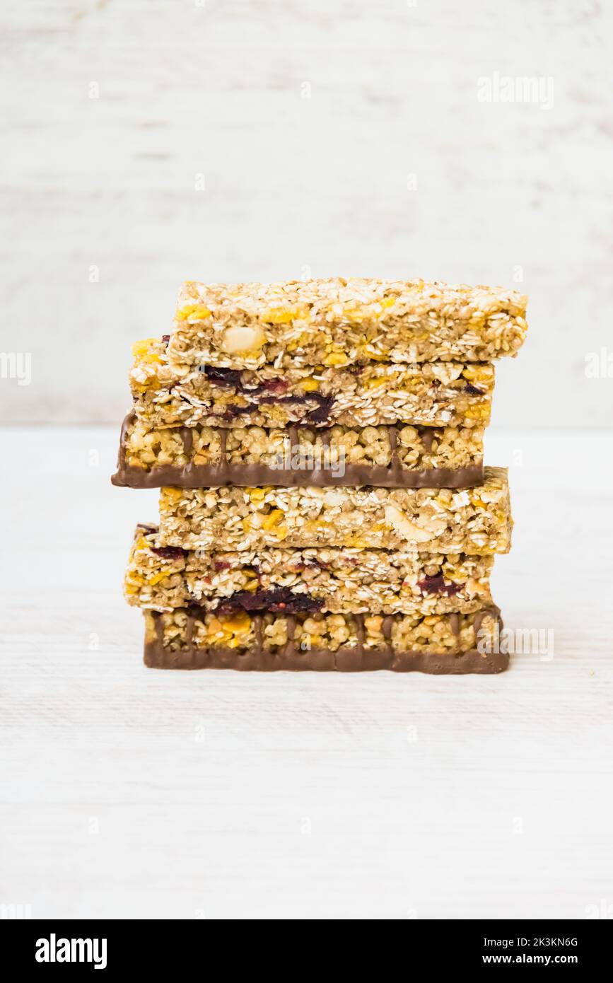 A pile of of various homemade granola bars with nuts, seeds, dark chocolate, honey and berries over a wooden background Stock Photo