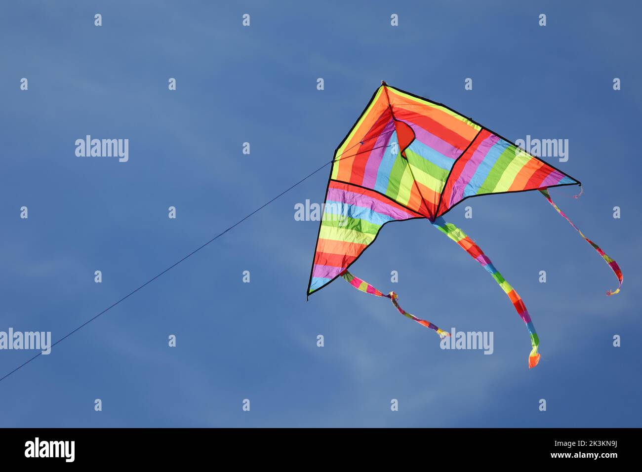 Kite with rainbow colors flying in the blue sky symbol of hope joy brotherhood Stock Photo