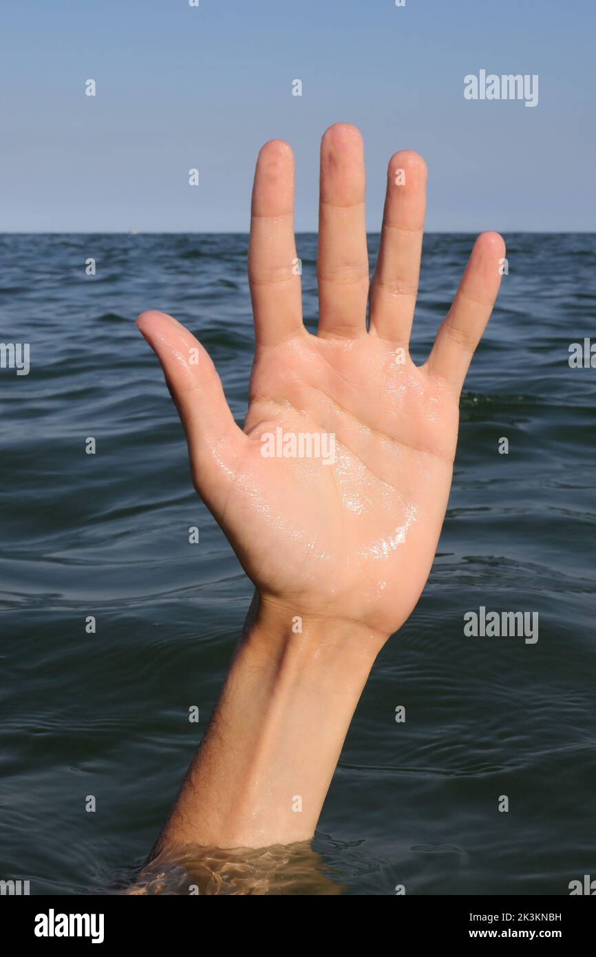 hand on the water of sea  of a person who is drowning and seeks help Stock Photo