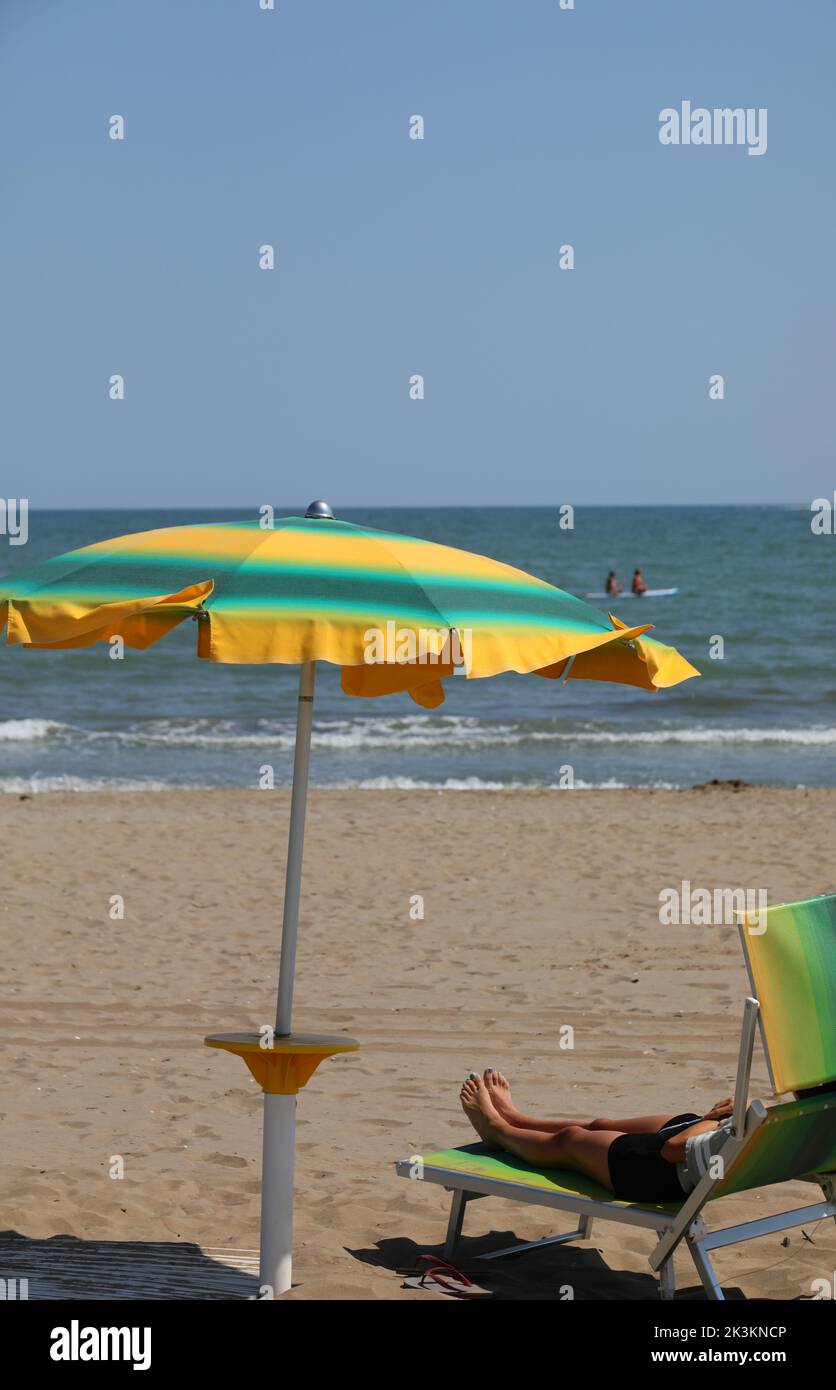 green and yellow colored sun umbrellas on the sandy beach by the sea Stock Photo