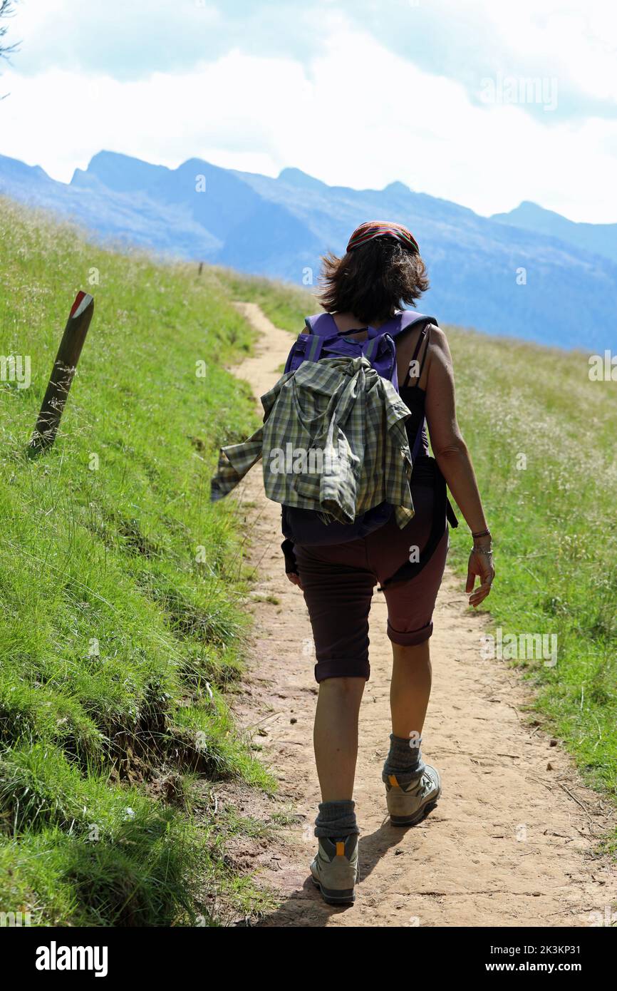 young female hiker while walking with backpack on shoulders in the trail Stock Photo