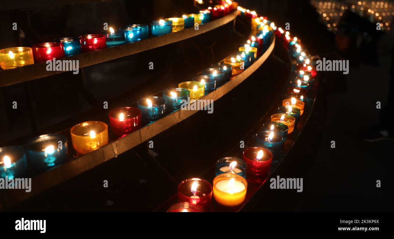 candles of various colors in the church for the prayers of the faithful during the religious ceremony Stock Photo