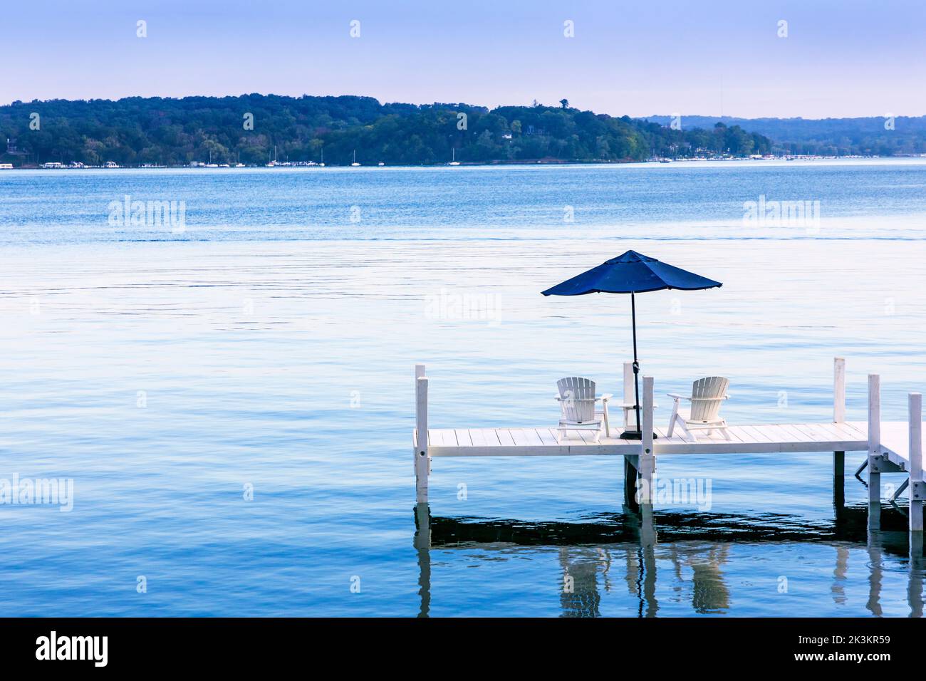 Wooden pier with deck chairs and a shade umbrella overlooking Lake Geneva, near Fontana, Wisconsin, America Stock Photo