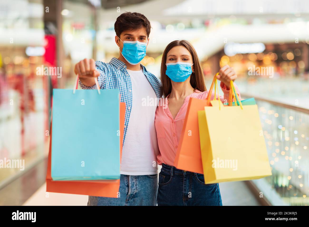 Couple Shopping Showing Shopper Bags Wearing Face Masks In Hypermarket Stock Photo