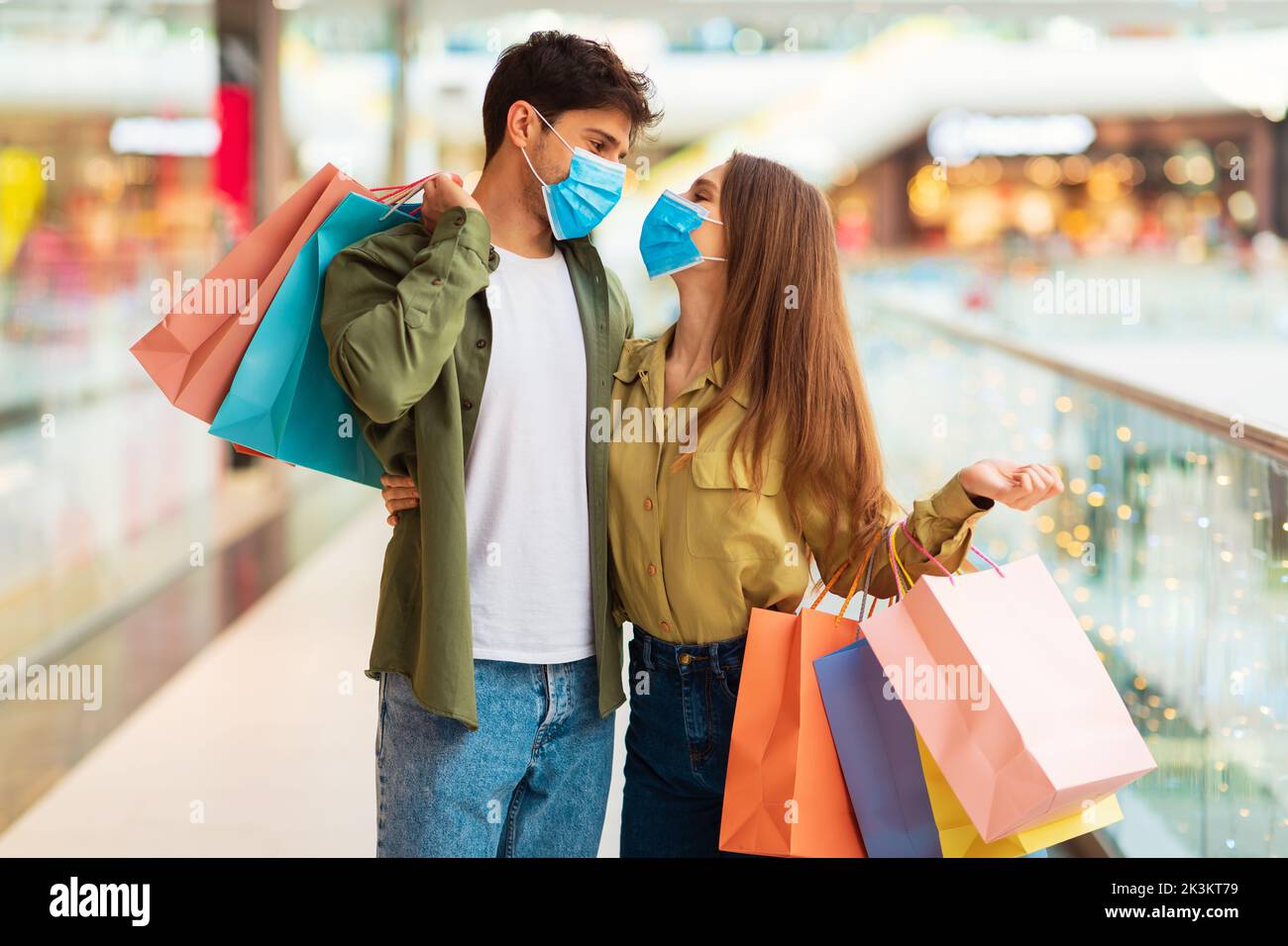 Couple Embracing Shopping Together Wearing Face Masks Standing In Hypermarket Stock Photo
