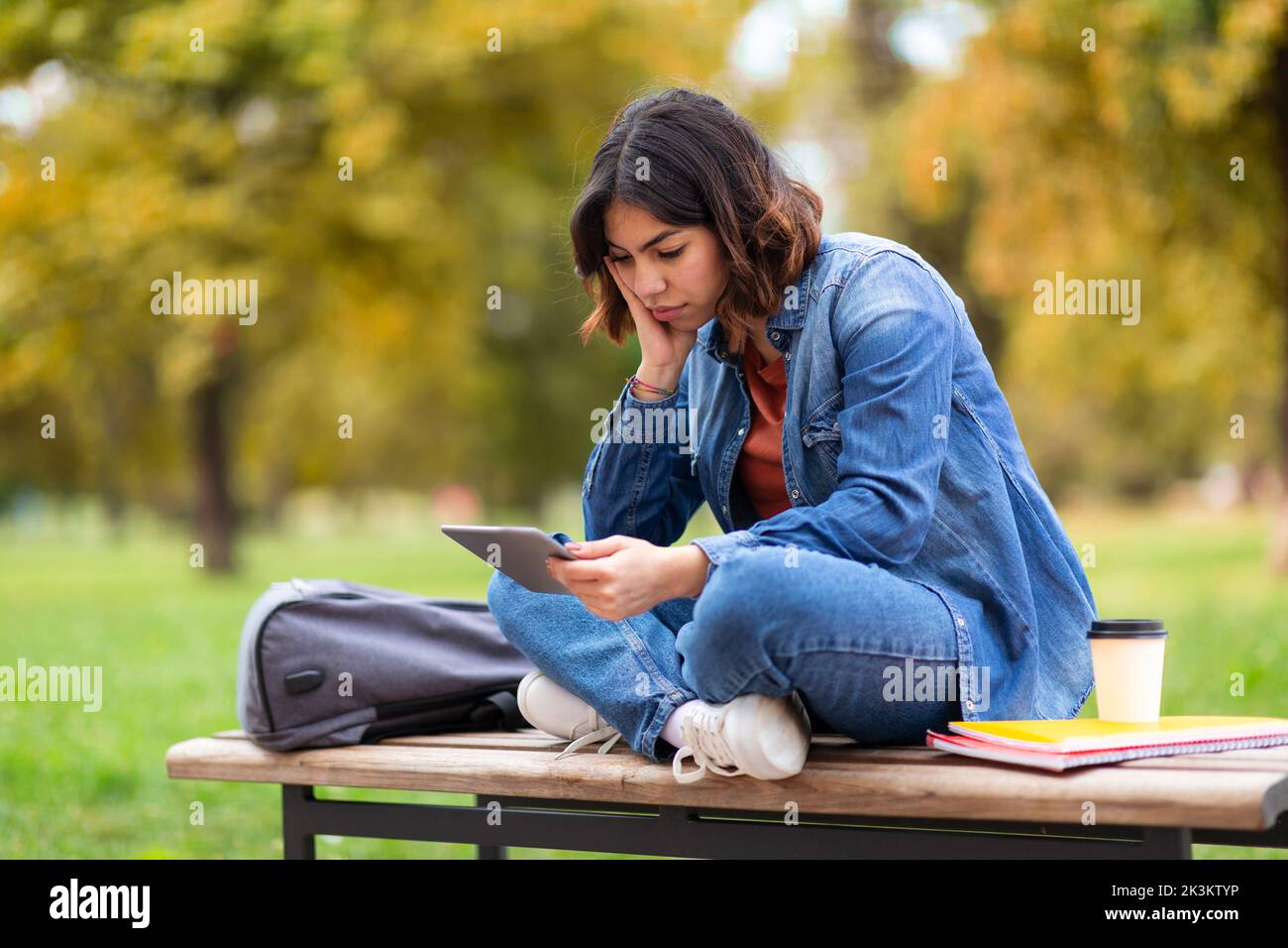 Tired Arab Student Woman Using Digital Tablet While Sitting On Bench Outdoors Stock Photo