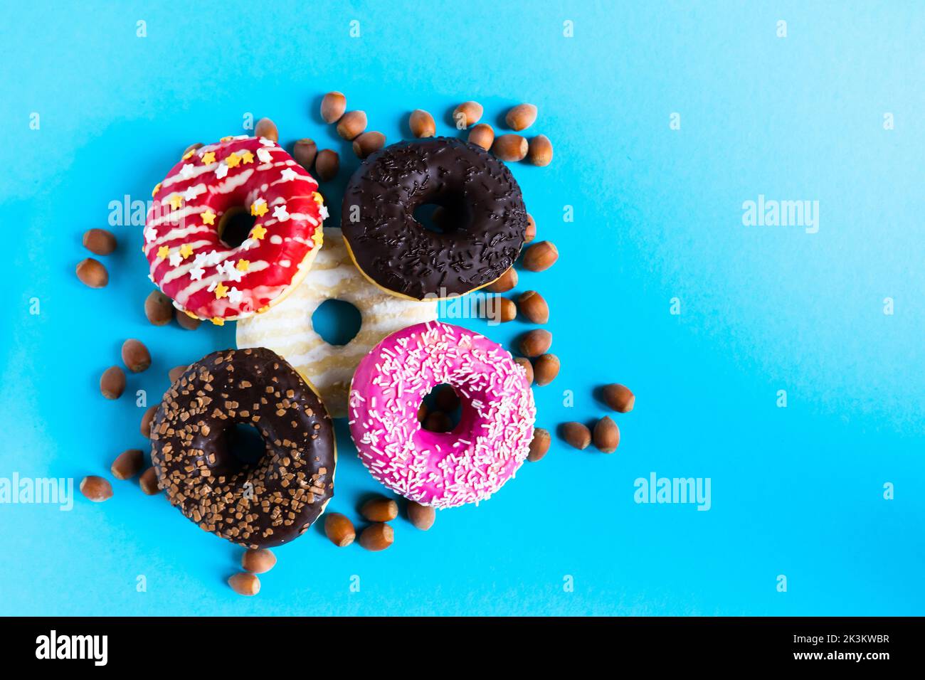 Donut with hazelnuts on blue background, close up Stock Photo